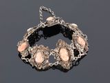 a silver bracelet with pink stones on a black surface