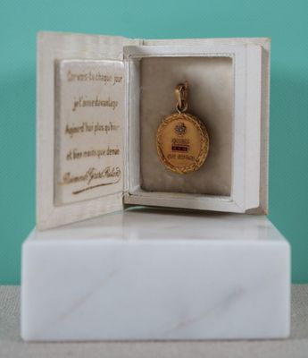 une petite boîte blanche contenant une médaille d'or