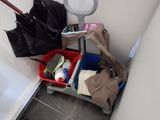 a bathroom with a toilet, a trash can, a bag and an umbrella
