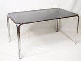 une table en verre avec des pieds chromés sur fond blanc
