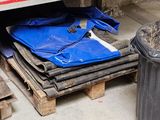 a blue tarp on the ground next to a trash can