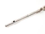 a silver flute that is laying on a white surface