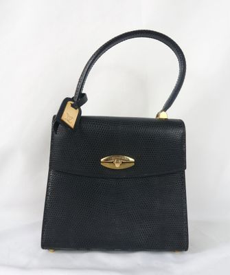 un sac à main en cuir noir avec des ferrures dorées sur la poignée