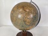 un vieux globe terrestre posé sur un socle en bois, avec un fond blanc