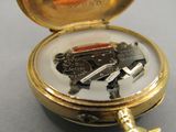 a small gold pocket watch with keys inside of it
