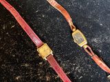 deux morceaux de cuir rouge ornés d'une boucle dorée sur un fond noir