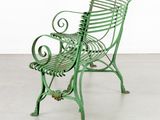 green metal garden bench in a white room with a white wall