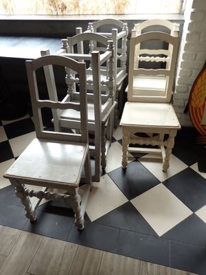 plusieurs chaises et une table dans une pièce au sol à carreaux noirs et blancs