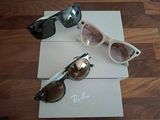 trois paires de lunettes de soleil posées sur une boîte, sur un plancher en bois