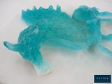 a blue dragon shaped jelly sitting on a white plate
