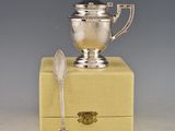 a silver cup sitting on top of a box next to a spoon