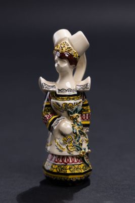 une image représentant une figurine de femme portant un chapeau et une robe