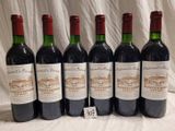 six bottles of wine are lined up on a table