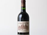 une bouteille de vin rouge posée sur une table en bois, avec un mur blanc en arrière-plan