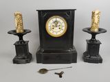 three candles and a clock sitting on a table