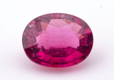 un gros plan d'une pierre précieuse rose de forme ovale posée sur une surface blanche