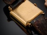 un gros plan d'une montre posée sur une surface noire, avec un bracelet en cuir
