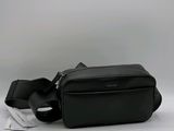 sac banane en cuir noir avec une lanière noire et une étiquette blanche sur le côté