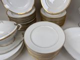 a lot of white and gold plates on the table