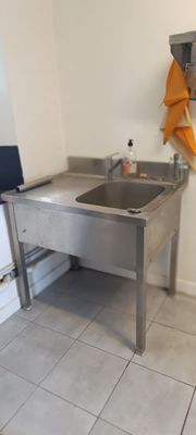 une cuisine avec un évier et un ordinateur portable posé sur le plan de travail