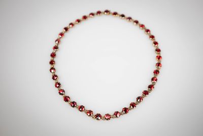 un gros plan d'un collier rouge et or posé sur une surface blanche