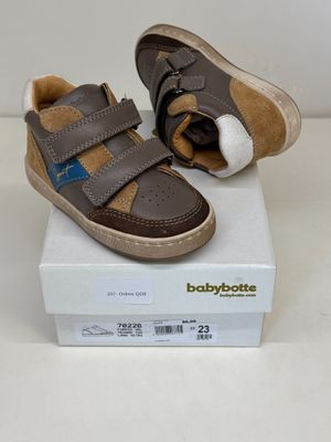 des chaussures Babybotte marron et beige posées sur une boîte, sur une surface blanche