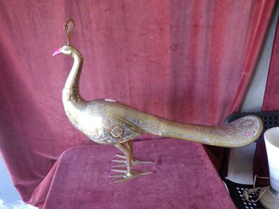 une statue de paon en or posée sur une table, à côté d'une tasse de café