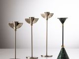 un ensemble de quatre bougeoirs en laiton posés sur une table blanche