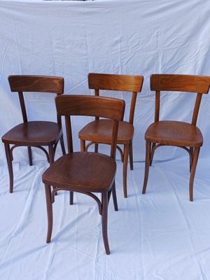 quatre chaises en bois sont alignées sur un fond blanc