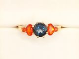 a close up of a ring with an orange and blue stone