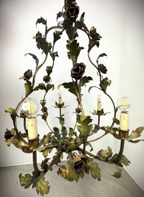 a chandelier with candles and flowers hanging from it