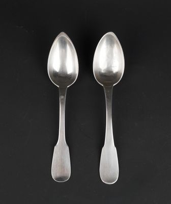 pair of silver spoons on a black surface with a black background