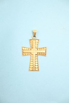 a gold cross pendant on a blue background