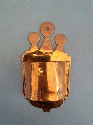 une clochette en or accrochée au mur, surmontée d'une couronne