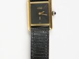 an image of a black and gold watch on a white surface