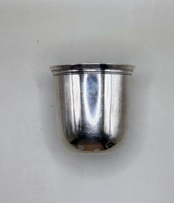 a silver cup that is sitting on a white surface