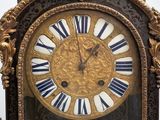 a clock that is sitting on a table with a statue in front of it