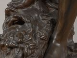 bronze statue of a man on a rock with his foot resting on a rock