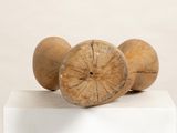 three wooden balls sitting on top of a white pedestal