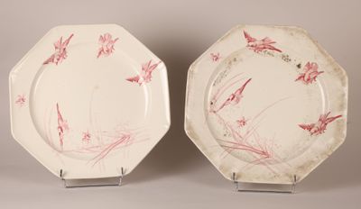 two plates with red and white designs on them sitting on a table