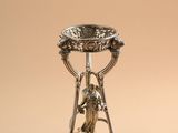 a silver plate with a bird on top of it on a stand