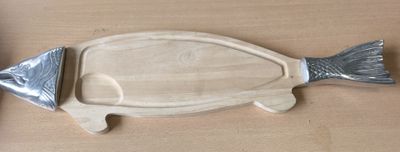 une planche à découper en forme de poisson sur laquelle est posé un couteau