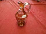 a glass pitcher on a red tablecloth with a label on it