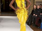 a woman that is walking down the runway in a yellow dress