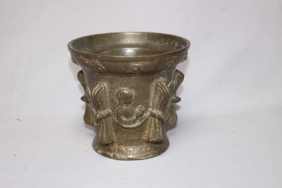un vase en argent orné d'un visage, posé sur une table