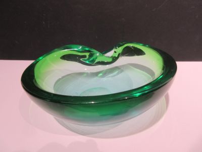 un saladier en verre vert posé sur une table blanche