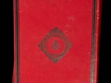 a red book sitting on top of a table next to a black background