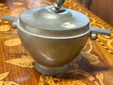 a silver pot on a wooden table in a room