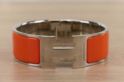 an orange bracelet with a silver clasp on a wooden surface