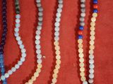 plusieurs colliers de différentes couleurs et tailles posés sur un fond rouge